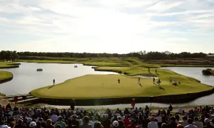 Golfer auf dem Grün am Le Golf National, umgeben von Wasser und Zuschauern.
