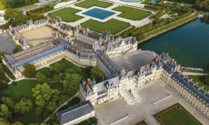 Luftaufnahme des prächtigen Schlosses Fontainebleau mit seinen weitläufigen Höfen, Gärten und einem See.