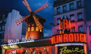 Das Moulin Rouge in Paris bei Nacht. Ein ikonisches Wahrzeichen mit leuchtenden Neonschildern und dem berühmten roten Windrad.