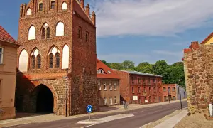 Historisches Stadttor in Templin Altstadt, mit Backstein und Feldsteinmauern. Dahinter rote Backsteingebäude und grüne Bäume.