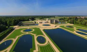 Das Chantilly Schloss mit seinen symmetrischen Wasserbecken und gepflegten Gärten, umgeben von einem weitläufigen Wald.