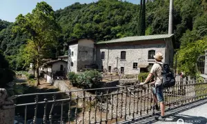 Mann mit Rucksack auf Brücke vor alter Steinmühle, ein echter Gardasee Geheimtipp.