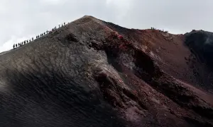 Wanderer erklimmen einen der beeindruckenden Vulkane in Europa, eine Reise durch schwarze Asche und rote Erde.