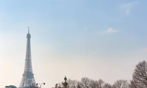 Eiffelturm ragt im winterlichen Paris in den blauen Himmel. Kahle Bäume säumen die Stadt.