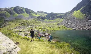 Drei Wanderer genießen die atemberaubende Berglandschaft und den klaren Bergsee beim St. Gallenkirch wandern.