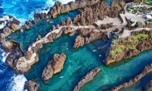 Natürliche Pools am **Strand Madeira**, umgeben von Felsen, mit klarem türkisfarbenem Wasser und badenden Menschen.