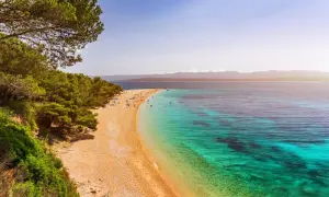 Traumhafter Strand auf einer kroatischen Insel mit Pinienwald und türkisfarbenem Wasser.