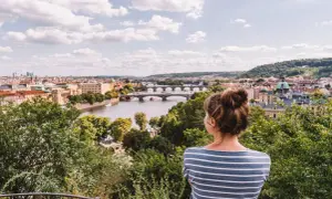 Frau genießt den Sommerblick auf Prag mit der Moldau und Brücken.