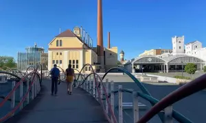 Zwei Personen spazieren über eine Brücke zur Pilsner Brauerei. Ein Geheimtipp für Bierliebhaber!