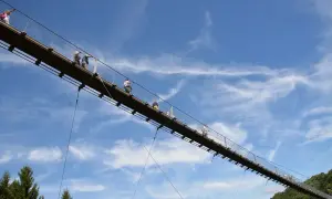 Menschen auf einer Hängebrücke, ein tolles Ausflugsziel in der Pfalz. Der blaue Himmel mit Wolken bildet die Kulisse.