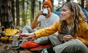 Ein Paar genießt Kaffee aus Metallbechern im Wald. Tolle Mikroabenteuer Ideen für eine Auszeit in der Natur.