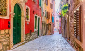 Eine Kopfsteinpflastergasse in Rovinj mit bunten Häusern. Entdecken Sie Rovinj Geheimtipps in dieser malerischen Gasse.
