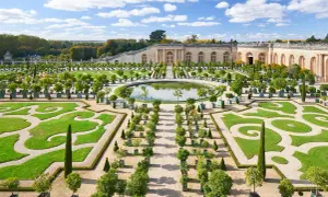Der Weg von Paris nach Versailles führt durch diesen prächtigen Garten mit symmetrischen Beeten, einem Spiegelteich und dem Schloss im Hintergrund.