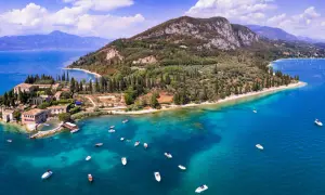 Punta San Vigilio: malerische Halbinsel mit historischen Gebäuden, Olivenhainen und dem türkisfarbenen Gardasee, belebt durch zahlreiche Boote.