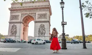 Frau in rotem Kleid tanzt vor dem Arc de Triomphe in Paris.