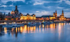 Dresden bei Nacht: beleuchtete Frauenkirche und Zwinger spiegeln sich im Wasser. Perfekte Reiseziele im November in Deutschland.