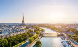 Paris im Sommer: Eiffelturm ragt über die Stadt, die Seine fließt friedlich, Boote liegen am Ufer. Ein malerischer Ausblick.