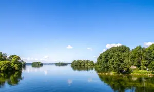 Idyllische Seenlandschaft in Norddeutschland mit grünen Ufern, Inseln und einem klaren blauen Himmel.