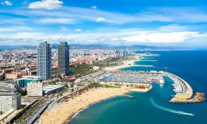 Blick auf den belebten barcelona strand mit Yachten im Hafen und der Skyline der Stadt im Hintergrund.
