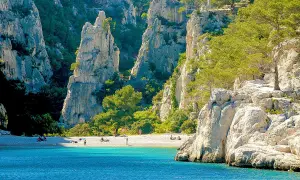 Sonnige Bucht mit türkisfarbenem Wasser und Felsen, ideal zum Calanques Baden. Menschen entspannen am Strand.
