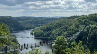 Hängebrucke über einem Fluss, umgeben von grünen Wäldern. Ein tolles Ziel für Ausflugsziele im Umkreis von 50 km.