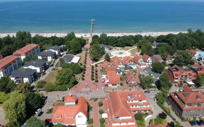 Luftaufnahme von Boltenhagen mit Strand, Promenade und roten Dächern. Hier finden sich viele Geheimtipps für einen entspannten Urlaub an der Ostsee.