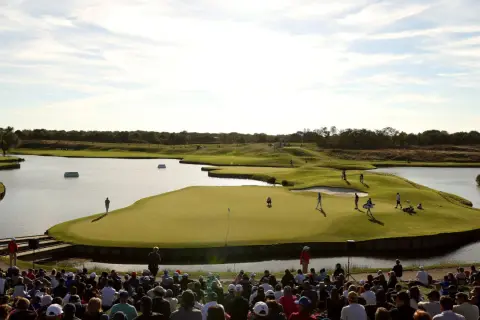 Golfer auf dem Grün am Le Golf National, umgeben von Wasser und Zuschauern.