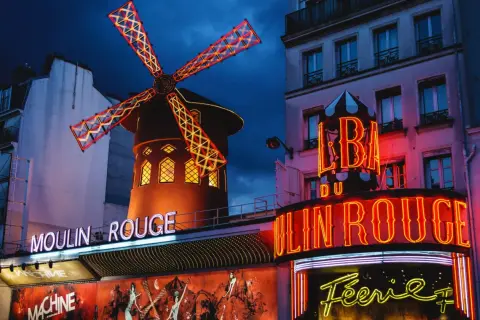 Das Moulin Rouge in Paris bei Nacht. Ein ikonisches Wahrzeichen mit leuchtenden Neonschildern und dem berühmten roten Windrad.