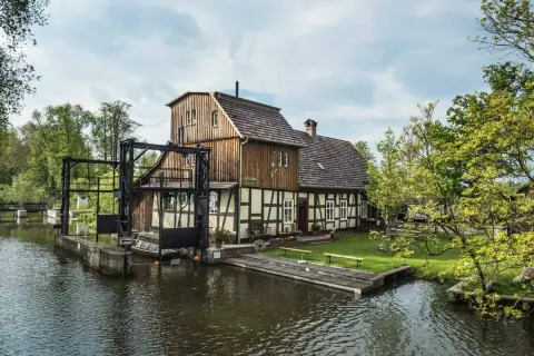 Historische Wassermühle am Wasser, perfekt für einen Spreewald Tagesausflug. Ein idyllischer Ort mit viel Grün und Wasser.