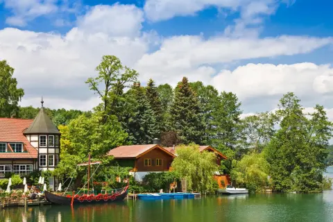 Ein Wikingerschiff liegt am Ufer, umgeben von Bäumen und Häusern. Ein echter Geheimtipp Mecklenburgische Seenplatte für Ruhesuchende.