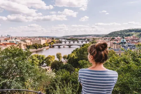 Frau genießt den Sommerblick auf Prag mit der Moldau und Brücken.