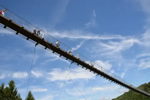 Menschen auf einer Hängebrücke, ein tolles Ausflugsziel in der Pfalz. Der blaue Himmel mit Wolken bildet die Kulisse.