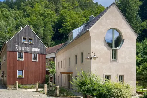 Almentalbaude im Nationalpark Refugium Schmilka, umgeben von üppigem Grün.