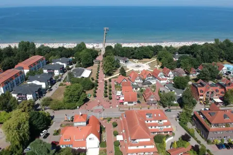 Luftaufnahme von Boltenhagen mit Strand, Promenade und roten Dächern. Hier finden sich viele Geheimtipps für einen entspannten Urlaub an der Ostsee.