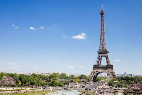 Eiffelturm, ein Paris must see, ragt in den blauen Himmel. Menschen genießen den sonnigen Tag im Park.