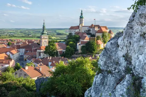 Malerische Stadtansicht von Mikulov, einem der schönsten orte tschechien, mit Schloss und Kirchturm vor grüner Hügellandschaft.