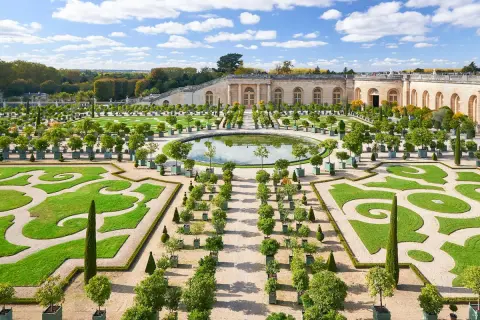 Der Weg von Paris nach Versailles führt durch diesen prächtigen Garten mit symmetrischen Beeten, einem Spiegelteich und dem Schloss im Hintergrund.