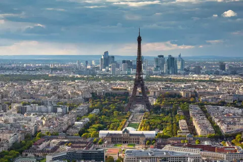 Paris in 2 Tagen: Eiffelturm ragt über die Stadt, umgeben von grünen Parks und Haussmann-Gebäuden. Im Hintergrund moderne Hochhäuser.
