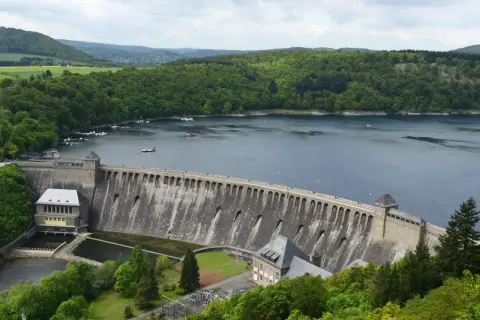 Stausee mit imposanter Staumauer, umgeben von grünen Wäldern. Ein tolles Ziel für Ausflugsziele Hessen, mit Booten auf dem Wasser.