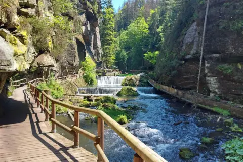 Holzstege schlängeln sich durch eine Schlucht mit Kaskaden. Ein perfekter Ort zum Hrensko wandern.
