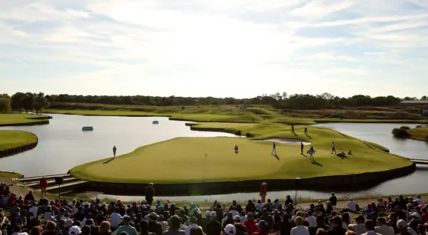 Golfer auf dem Grün am Le Golf National, umgeben von Wasser und Zuschauern.