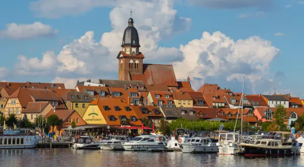 Hafen mit vielen Booten und einem Restaurant, hinter dem sich eine Stadt mit Kirchturm und roten Dächern erstreckt. Perfekte ausflugsziele waren.