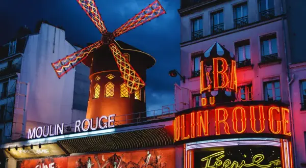 Das Moulin Rouge in Paris bei Nacht. Ein ikonisches Wahrzeichen mit leuchtenden Neonschildern und dem berühmten roten Windrad.