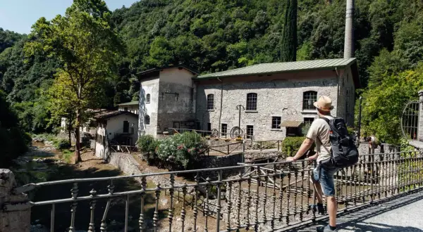 Mann mit Rucksack auf Brücke vor alter Steinmühle, ein echter Gardasee Geheimtipp.
