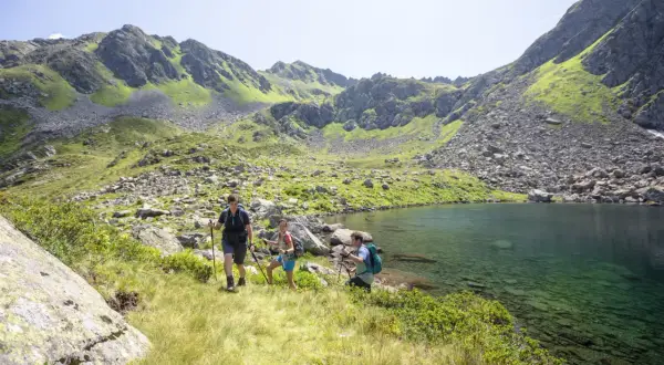 Drei Wanderer genießen die atemberaubende Berglandschaft und den klaren Bergsee beim St. Gallenkirch wandern.