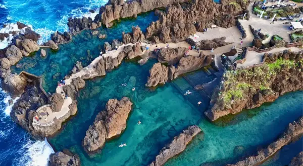 Natürliche Pools am **Strand Madeira**, umgeben von Felsen, mit klarem türkisfarbenem Wasser und badenden Menschen.