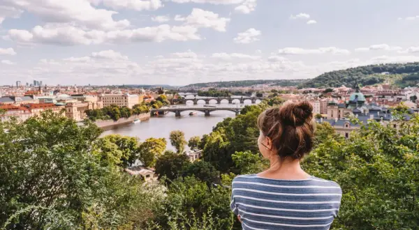 Frau genießt den Sommerblick auf Prag mit der Moldau und Brücken.