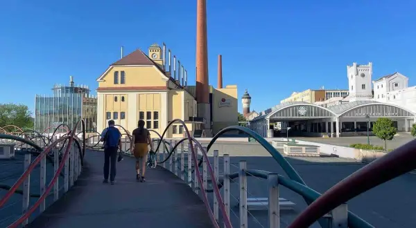 Zwei Personen spazieren über eine Brücke zur Pilsner Brauerei. Ein Geheimtipp für Bierliebhaber!