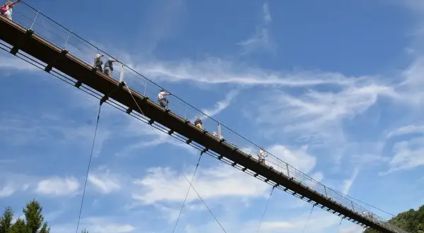 Menschen auf einer Hängebrücke, ein tolles Ausflugsziel in der Pfalz. Der blaue Himmel mit Wolken bildet die Kulisse.