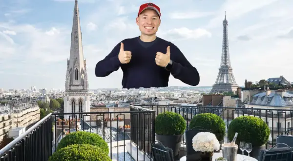 Mann mit Daumen hoch vor Pariser Skyline, mit Eiffelturm und Kirchturm. Ein Traum von der Avenue Montaigne.